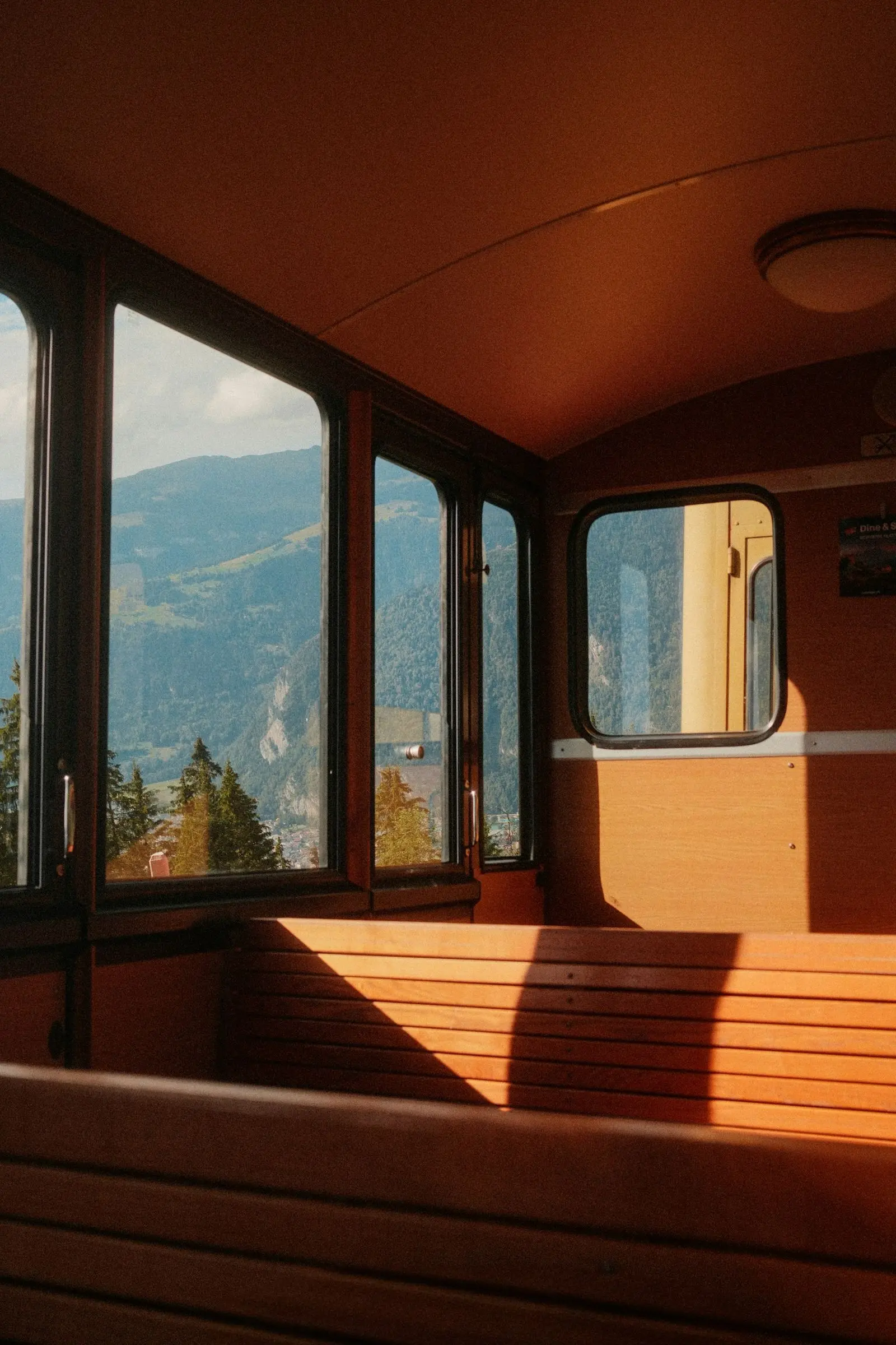 Voiture de train en bois vide, fenêtres ouvertes sur une vallée alpine