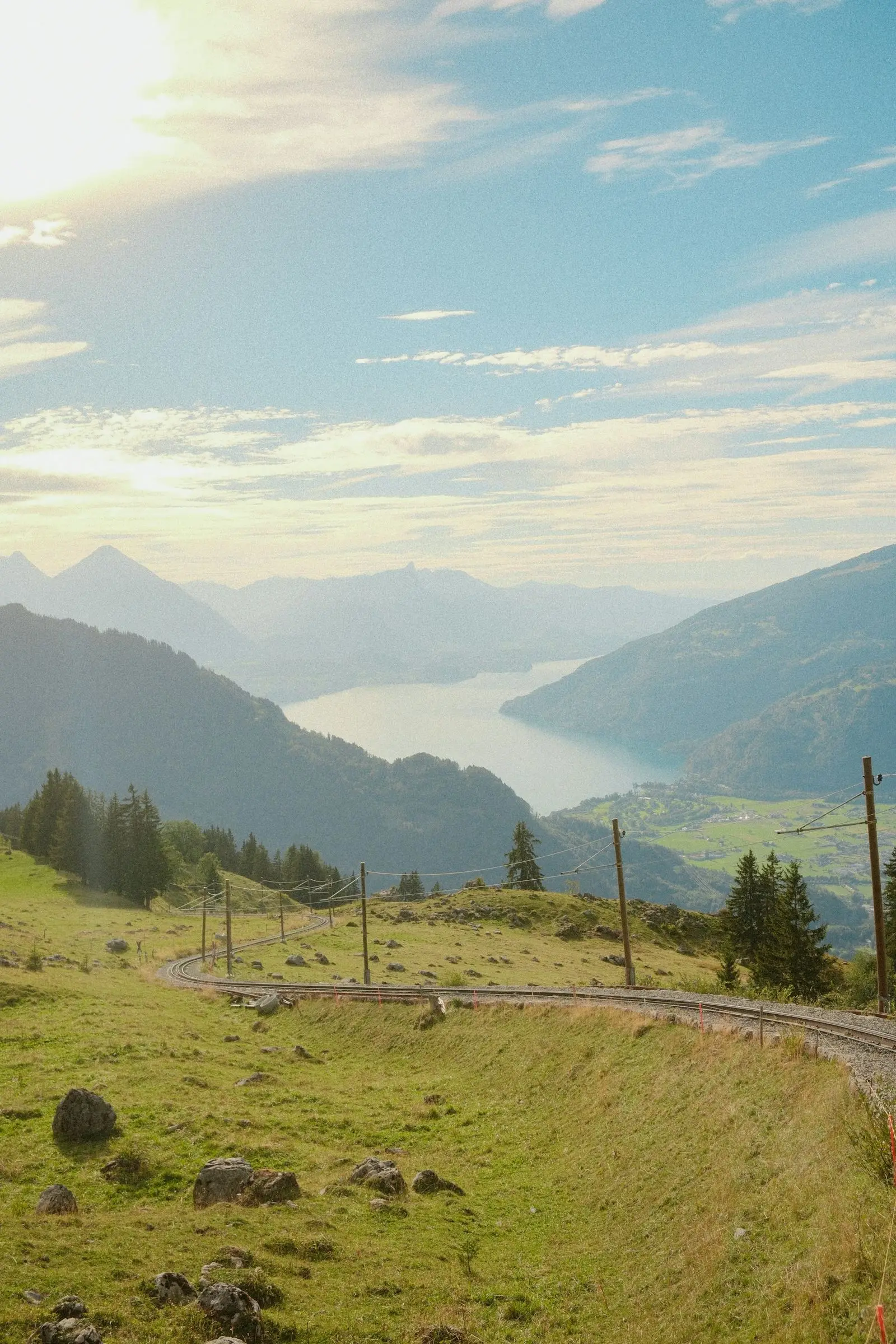 Voie ferrée serpentant dans les alpages au-dessus d'un lac suisse